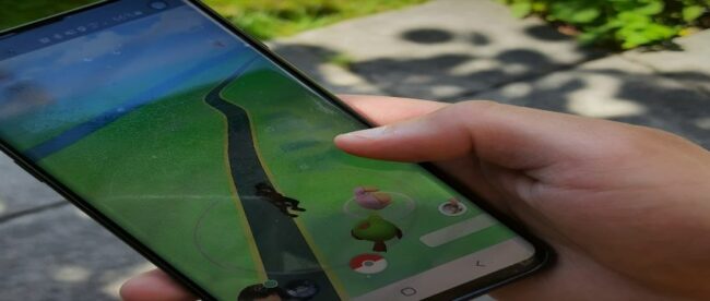 Das Bild zeigt eine Hand, die ein Smartphone hält, auf dem die App Pokémon Go geöffnet ist